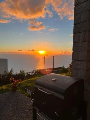 a briefcase sitting on a bench in front of a sunset at Cozy Sea View House Fajã da Ovelha in Calheta