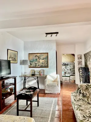 a living room with a couch and a tv at Cozy Sea View House Fajã da Ovelha in Calheta