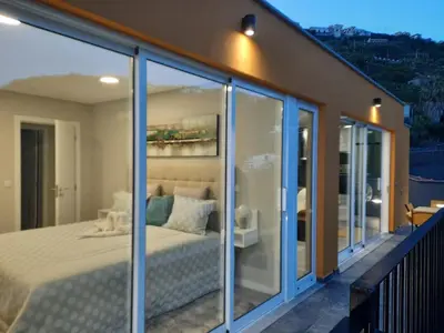 a bedroom with glass doors and a bed on a balcony at Zeza´s Sky in Calheta