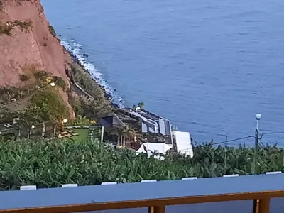 a house on the side of a cliff next to the water at Zeza´s Sky in Calheta