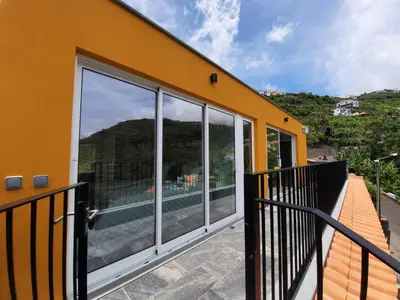 a balcony of a house with large glass windows at Zeza´s Sky in Calheta