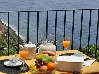 a table with fruit and juice on a balcony at Zeza´s Sky in Calheta