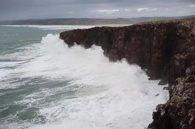 an ocean wave crashing against a rocky cliff at Coureladaltura in Aljezur