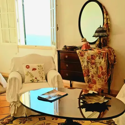 a living room with a table and a chair and a mirror at Quinta do Cabouco in Ribeira Brava