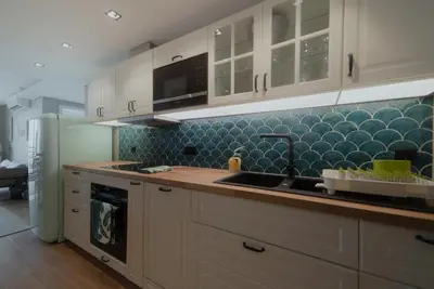 a kitchen with white cabinets and blue tiles at Rooftop Marina l by Madeira Best Apartments in Funchal