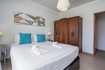 a bedroom with a large white bed with blue pillows at Stunning sea view apartment in Burgau #1897 in Burgau