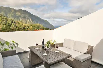 a balcony with a table with wine glasses on it at Sebastian's Apartment in São Vicente