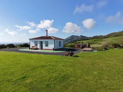a small white house in a field of grass at Casita - Cantinho do Paraíso in Vila do Porto