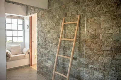 a wooden ladder in a room with a brick wall at Casita - Cantinho do Paraíso in Vila do Porto