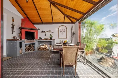 an outdoor patio with a table and a fireplace at São Jorge Cottage - By WeHost in Santana