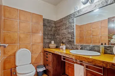 a bathroom with a sink and a toilet and a mirror at São Jorge Cottage - By WeHost in Santana