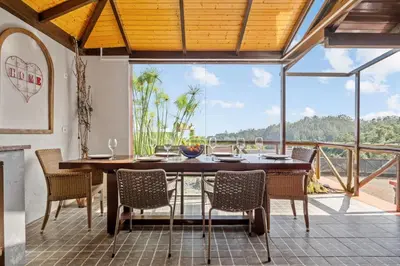 a dining room with a table and chairs on a balcony at São Jorge Cottage - By WeHost in Santana