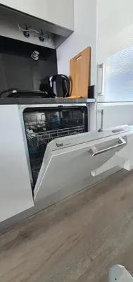 a kitchen with an open dishwasher in a kitchen at Apartamento T2-5m Aeroporto CR7 in Santa Cruz