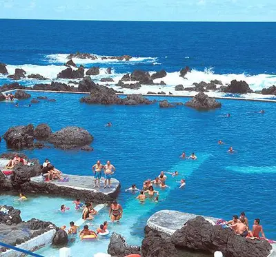 a group of people swimming in the blue ocean at Apartamento T2-5m Aeroporto CR7 in Santa Cruz