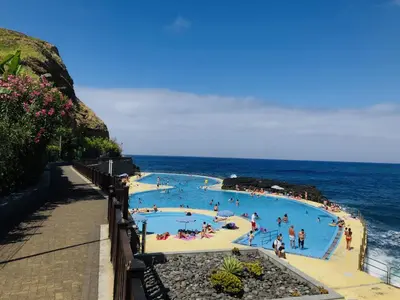 a group of people in a swimming pool next to the ocean at Apartamento T2-5m Aeroporto CR7 in Santa Cruz