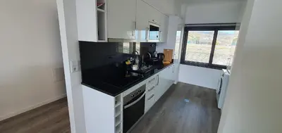 a kitchen with white cabinets and a black counter top at Apartamento T2-5m Aeroporto CR7 in Santa Cruz