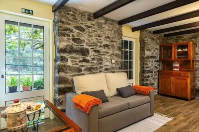 a living room with a couch and a stone wall at Villa Rústica - Casa da Lurdes in Ribeira Brava