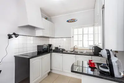 a kitchen with white cabinets and a black counter top at Newly renovated 2 bedroom townhouse - close to Salema Beach in Salema