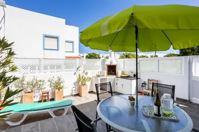 a patio with a table and a green umbrella at Newly renovated 2 bedroom townhouse - close to Salema Beach in Salema