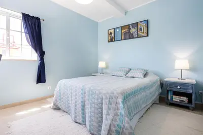 a blue bedroom with a bed and a window at Newly renovated 2 bedroom townhouse - close to Salema Beach in Salema
