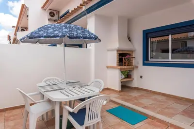 a patio with a table and chairs and an umbrella at Casa dos Sonhos in Luz