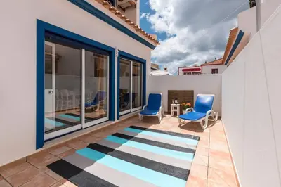 a patio with two blue chairs and a rug at Casa dos Sonhos in Luz