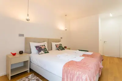 a bedroom with a large white bed and a table at FLH Funchal Balcony Flat with Pool in Funchal