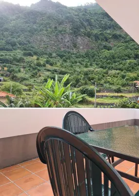a table and chairs on a balcony with a view of a mountain at Scenic Comfort in Ponta Delgada