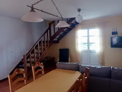 a living room with a table and a staircase at Scenic Comfort in Ponta Delgada