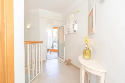 a hallway with white walls and a table with flowers on it at Beautiful Villa on Boavista Golf Resort - Daily Service & Spa Access in Lagos