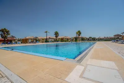 a swimming pool at a resort with palm trees at Beautiful Villa on Boavista Golf Resort - Daily Service & Spa Access in Lagos