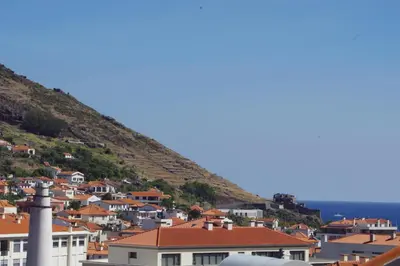a town on a hill with houses and the ocean at Machico Comfort in Machico