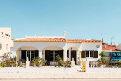 a white house with black windows and a blue bus at LemonTree Eco Surfhouse in Sagres