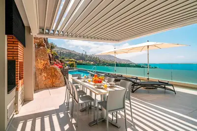 a patio with a table and chairs and a view of the ocean at OurMadeira - GrandView in Funchal