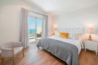 a bedroom with a bed and a chair and a window at OurMadeira - GrandView in Funchal