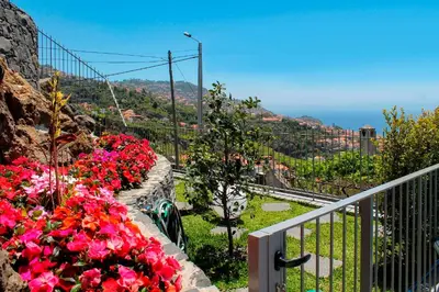 a balcony with pink flowers and a view of the ocean at OurMadeira - GrandView in Funchal