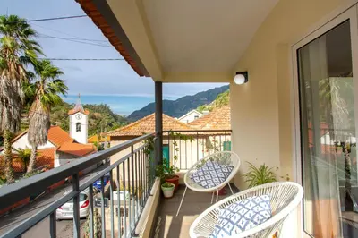 a balcony with two chairs and a view of a town at A Casa da Tia in São Vicente