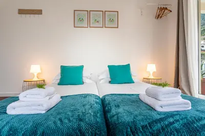 two twin beds in a bedroom with blue pillows at A Casa da Tia in São Vicente