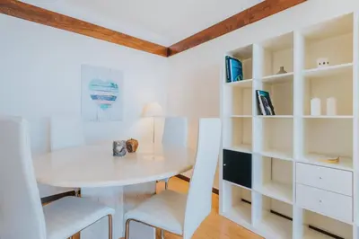 a white dining room with a table and white shelves at come hear the ocean! in Funchal
