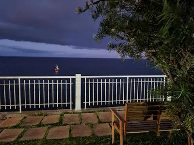 a wooden bench sitting next to a white fence at come hear the ocean! in Funchal