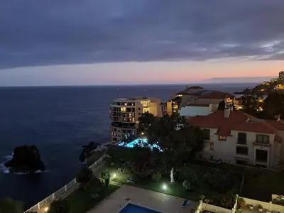 an aerial view of a city and the ocean at night at come hear the ocean! in Funchal
