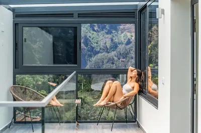 a woman sitting in a chair on the balcony of a house at Coração da Madeira by Homie in Curral das Freiras