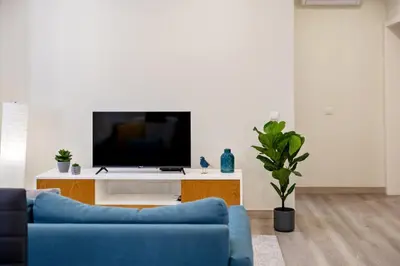 a living room with a blue couch and a tv at Coração da Madeira by Homie in Curral das Freiras