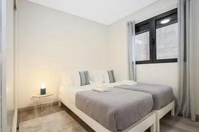 two beds in a white room with a window at Coração da Madeira by Homie in Curral das Freiras