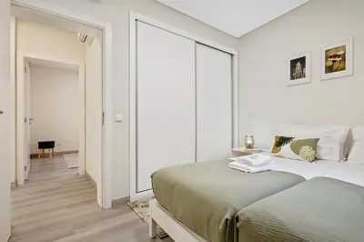 a white bedroom with a large bed and a hallway at Coração da Madeira by Homie in Curral das Freiras