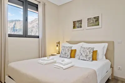 a white bedroom with a bed with towels on it at Coração da Madeira by Homie in Curral das Freiras