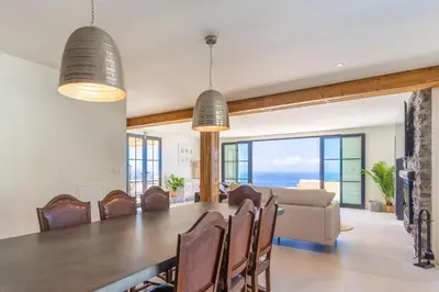 a dining room and living room with a table and chairs at Villa Horizonte Azul by Holiday Rental Madeira in Ponta do Sol