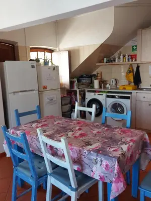 a kitchen with a table with chairs and a refrigerator at Agua de Sonho 2 in Bensafrim