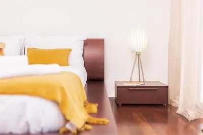 a bedroom with a bed with a yellow blanket and a lamp at Villa Amplitude in Câmara de Lobos