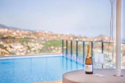 a bottle of champagne sitting on a table next to a pool at Villa Amplitude in Câmara de Lobos